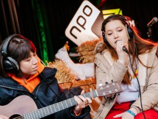Jeugdzorg-ervaringsdeskundige Carlijn speelt haar liedje met MEAU bij het Glazen Huis