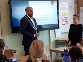 Burgemeester Ahmed Marcouch voor de klas met jongetje dat spreekbeurt over hem houdt