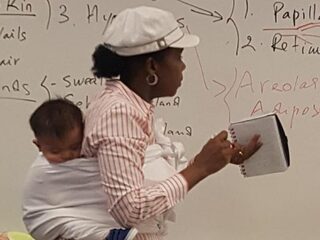 Lerares draagt baby van studente bij zich tijdens les