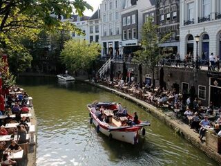 Man pist in Utrecht vanaf gracht op terrasbezoekers