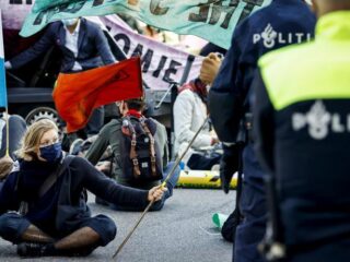 Klimaatactivisten blokkeren kruispunt in Amsterdam ondanks verbod