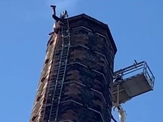 Man hangt al urenlang ondersteboven aan 90 meter hoge schoorsteen