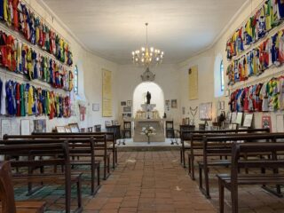 Het peloton flitst langs Le Notre Dame des Cyclistes om oude helden te eren