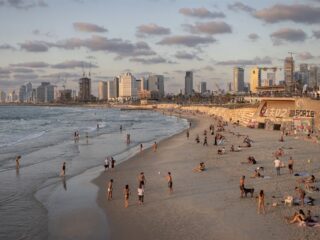 Strandtas en vluchtkoffer staan naast elkaar in Libanon terwijl Israëlische straaljagers overvliegen