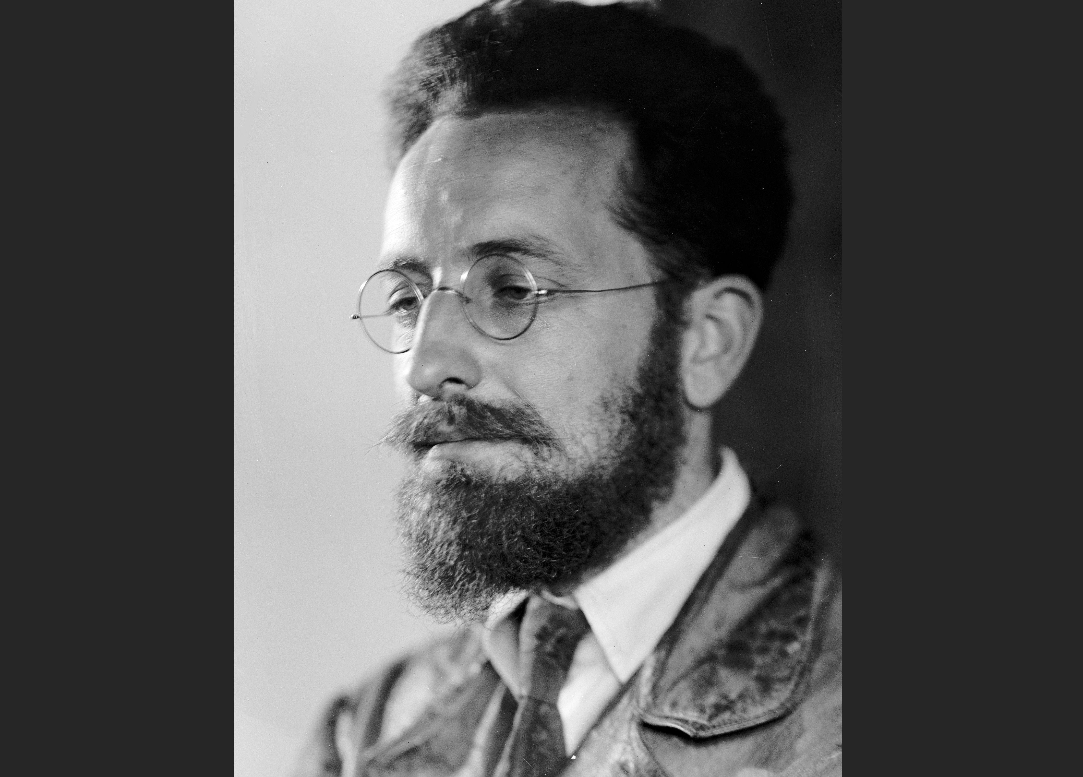 Een zwart-wit foto van Charles Seeger. Hij is een man met donker haar en een baard en snor. Hij draagt een ronde bril.