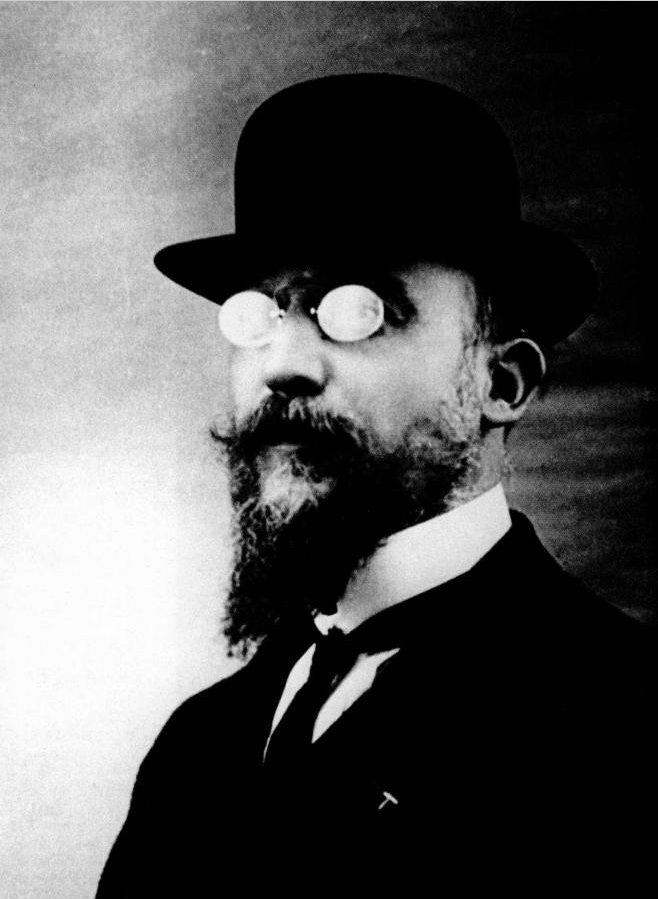 Een foto van de componist Erik Satie in één van zijn pakken met een bolhoed en een excentriek brilletje.