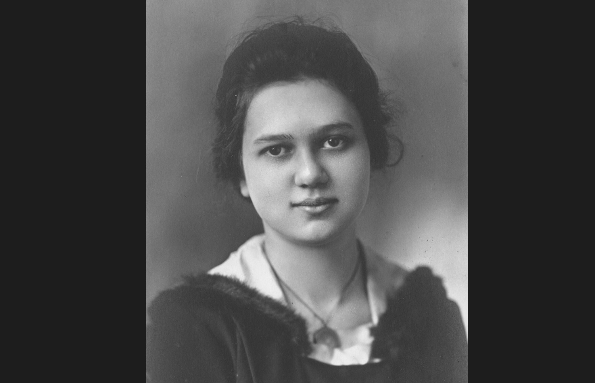 Een zwart-wit afbeelding van Ruth Crawford Seeger uit de jaren 20, toen ze een jonge vrouw was. Ze heeft een rond gezicht en donker haar.