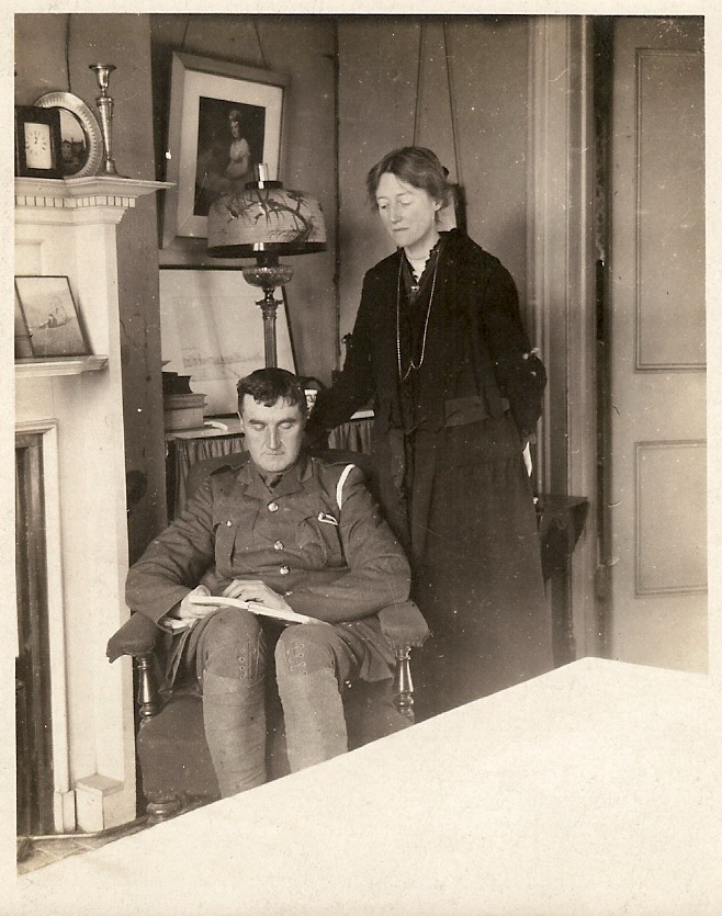 Ralph Vaughan Williams zit in uniform in een stoel met een boek op schoot, zijn Adeline Vaughan Williams staat ernaast met haar hand op de rugleuning. Een foto gemaakt in 1917.