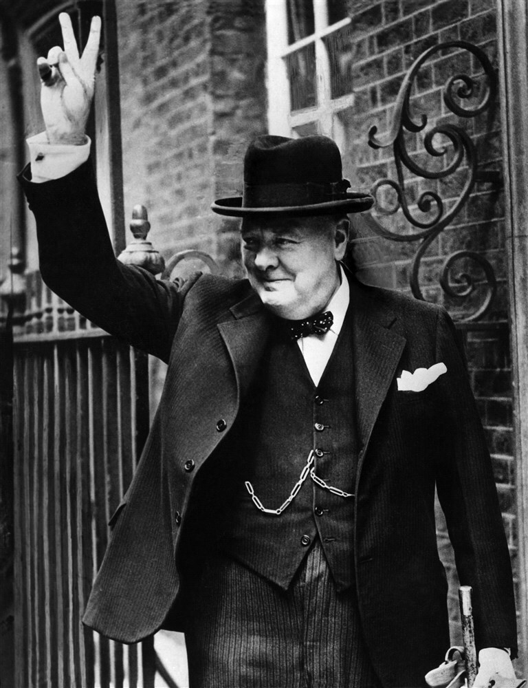 Premier Winston Churchill maakt het V-teken met zijn hand.